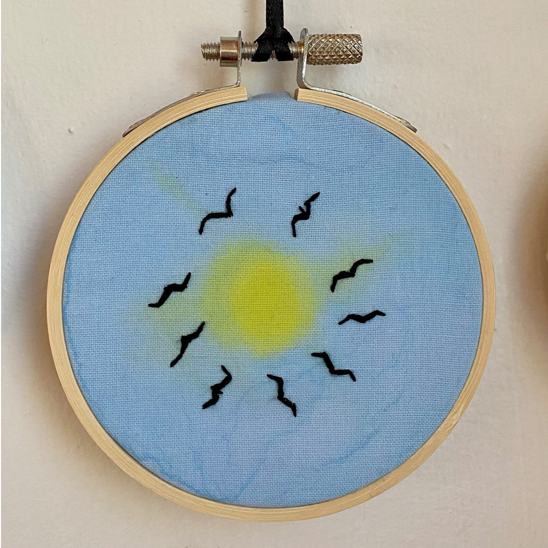 an embroidery of birds circling in the sky