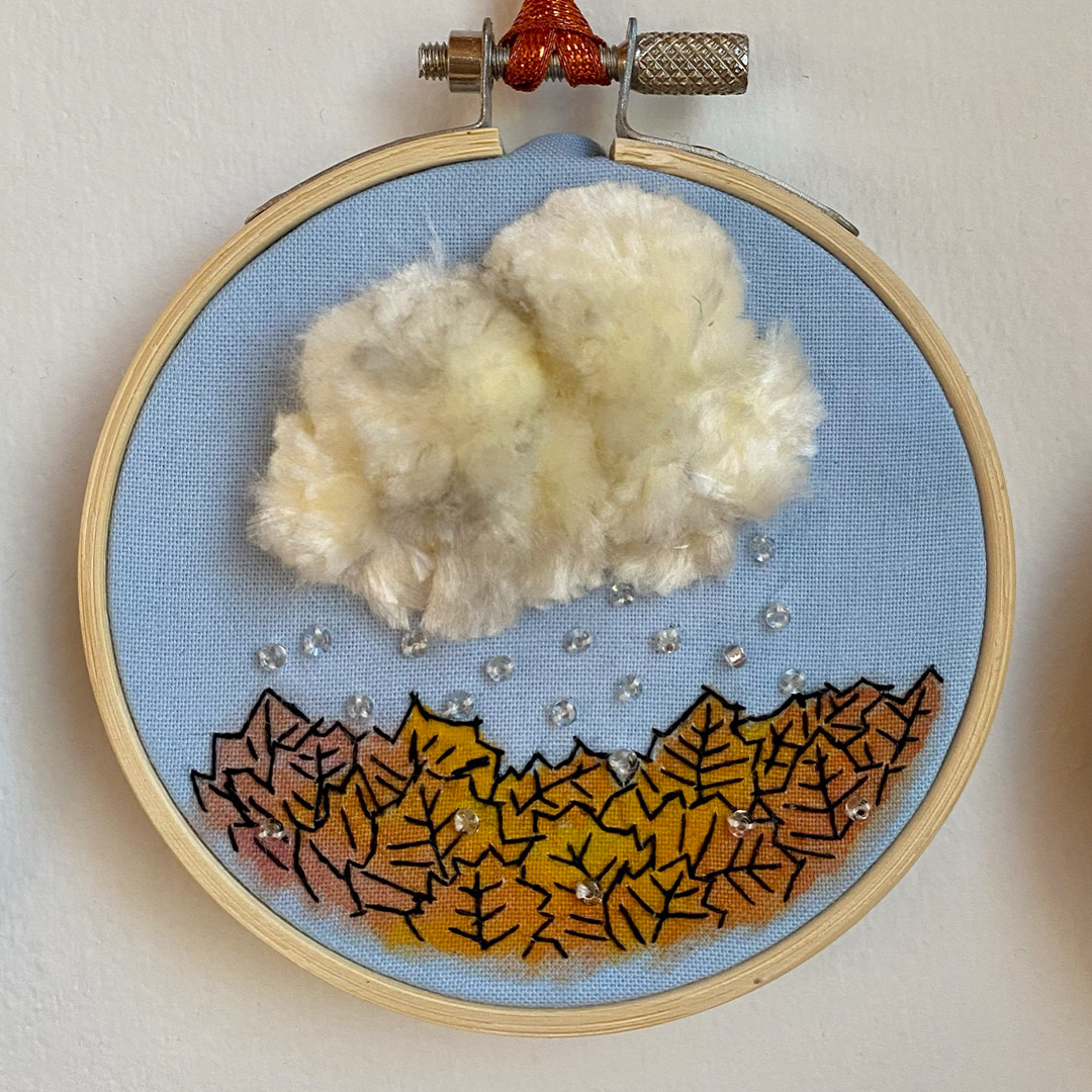 an embroidery of a cloud over autumn leaves