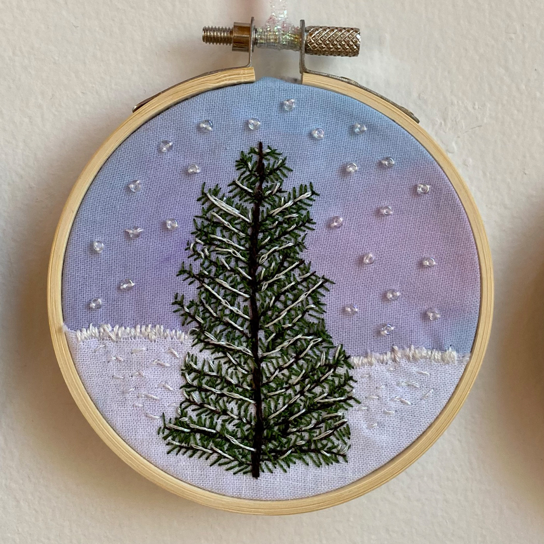 an embroidery of a pine tree with snow