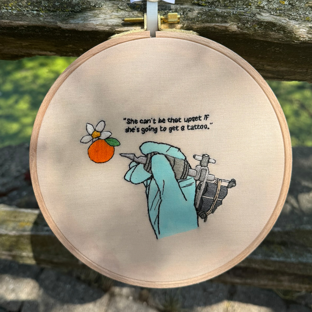 an embroidery of a tattoo gun with words